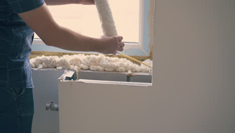 happy-man-applies-spray-foam-insulation-on-sill-in-room