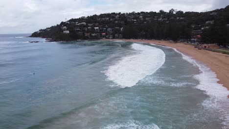 Drone-flying-over-beautiful-sandy-beach-in-Australia-on-a-cloudy-day