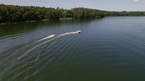 Motorboat-pulls-Cockpit-Tube-on-a-lake,-following-drone-shot