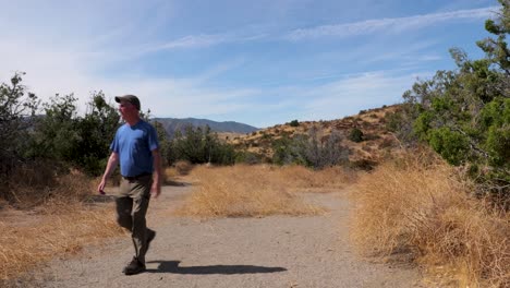 Hombre-Caucásico-Camina-En-El-Desierto-Suroeste,-California-Cerca-De-Formaciones-Rocosas