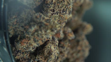 A-vertical-macro-cinematic-detailed-shot-of-a-cannabis-plant,-orange-hybrid-strains,-Indica-and-sativa-,black-marijuana-flower,-on-a-rotating-stand,-slow-motion,-4K-video,-professional-studio-light