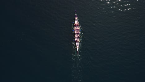 Dragonboat-alone-swims-on-a-lake,-top-down-drone-shot