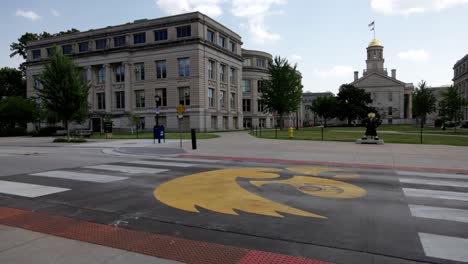 Old-Capitol-building-and-Hawkeye-statue-on-the-campus-of-the-University-of-Iowa-in-Iowa-City,-Iowa-with-gimbal-video-panning-left-to-right-wide-shot