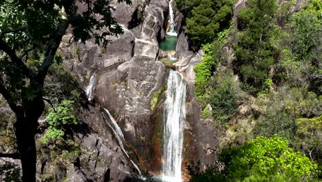Tilt-down-shot-of-natural-cascading-waterfall-in-Peneda-Gerês-Nationalpark,-Portugal---wide-shot-slow-motion