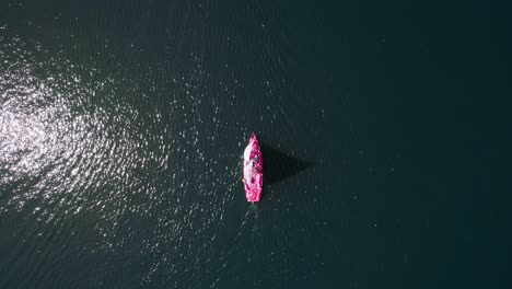Sailboat-on-a-deeply-blua-lake,-dron-top-down-shot