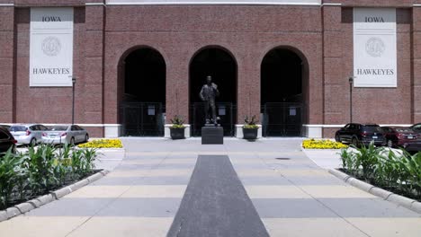 Escultura-De-Bronce-De-Nile-Kinnick-En-El-Estadio-Kinnick-En-El-Campus-De-La-Universidad-De-Iowa-En-La-Ciudad-De-Iowa,-Iowa-Con-Video-De-Cardán-Caminando-Hacia-Adelante.