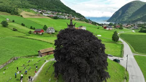 Hopperstad-Stave-Church-in-Vik-in-Sogn-Norway-with-tourists-on-guided-tour-outside-during-summer---Aerial