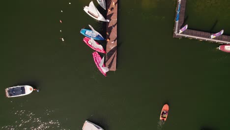 Lake-platform-with-people-and-boats-near-it,-top-down-drone-shot