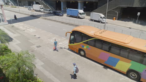 Toma-Panorámica-Desde-Arriba-O-Personas-Caminando-Junto-A-Un-Autobús-En-Una-Calle-Tranquila-En-Hong-Kong,-Asia