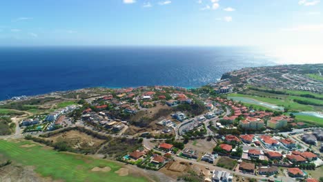 Beautiful-coastal-seaside-village-town-overlooks-blue-expanse-ocean-horizon,-aerial
