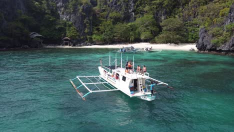 Inselhüpfende-Touristen-Auf-Dem-Oberdeck-Eines-Traditionellen-Auslegerbootes-Mit-Blick-Auf-Den-Tropischen-Serenity-Beach-Auf-Der-Insel-Cadlao,-El-Nido,-Philippinen