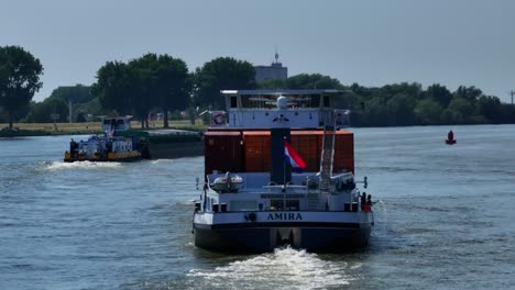 A-cargo-ship-with-colorful-containers-transports-cargo-on-the-river-with-the-Netherlands-flag-flying