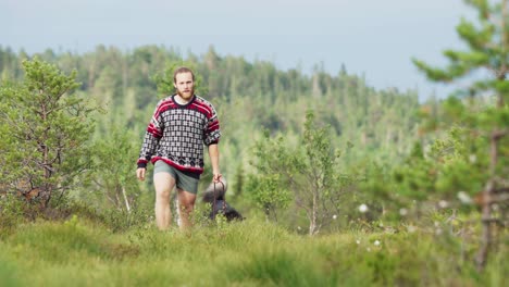 Man-Walking-With-Alaskan-Malamute-Dog-In-The-Countryside-Of-Norway