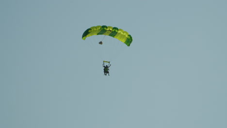 Two-Adult-People-Flying-With-A-Parachute-At-A-High-Altitude-Against-Clear-Sky