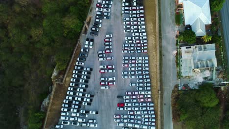 Cars-parked-at-harbor-port-ready-for-transport-export-import-on-barge-ship,-aerial-top-down-pan
