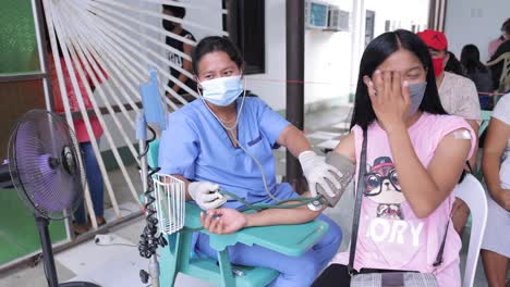 Asiatische-Krankenschwester,-Die-Das-Blutdruck-Covid-Screening-Einer-Frau-Durchführt