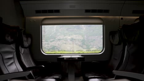 Un-Vagón-De-Tren-Vacío-De-Clase-Ejecutiva-Con-Una-Vista-Panorámica-De-La-Campiña-Suiza-Que-Pasa-Por-La-Ventana,-Suiza