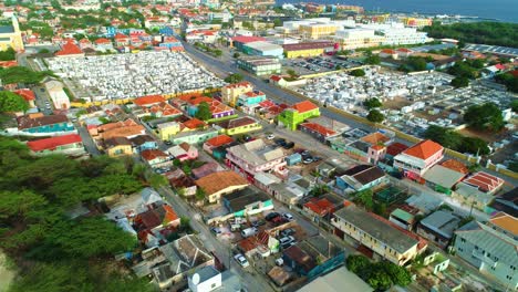 Drone-push-in-over-bright-yellow-and-orange-buildings-in-industrial-lots-of-Curacao