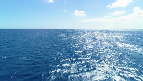 Aerial-dolly-above-empty-ocean-water-glistening-shining-from-light-on-ripples-and-windy-waves