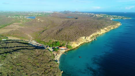 Caribbean-beach-cove-at-valley-gorge-by-turquoise-Caribbean-ocean-water,-aerial-panoramic,-Kokomo-beach-Curacao