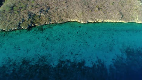 Die-Drohne-Steigt-Und-Neigt-Sich-Entlang-Des-Trockenen-Küstenbergs-Und-Des-Inneren-Riffs,-Um-Im-Meer-Abzufallen