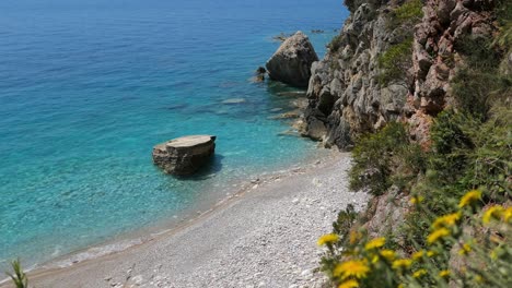 Hidden-beach-with-turquoise,-clear-blue-water,-Mediterranean,-reveal-shot