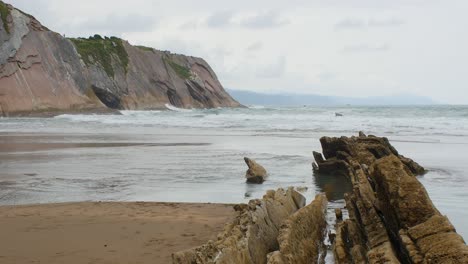 Ocean-waves-crash-on-shallow-beach-water-of-Playa-de-Itzurun,-Zumaia,-static