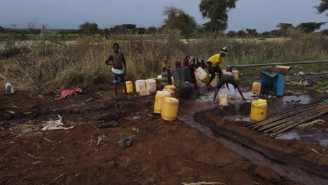 Los-Niños-Africanos-Llenan-Recipientes-De-Plástico-Con-Agua-Dulce-Del-Pozo,-Kenia