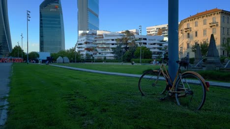 An-Der-Stange-Befestigtes-Fahrrad-Auf-Der-Piazzale-Giulio-Cesare,-Im-Hintergrund-Die-Skyline-Von-Zaha-Hadids-Wohnanlage,-Citylife,-Mailand,-Italien