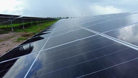 Wet-solar-panel-close-up-tilt-up-view-after-a-rainstorm-reflecting-under-a-cloudy-sky,-efficiency-testing-of-photovoltaic-energy-farm