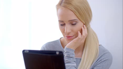 Serious-young-woman-reading-on-her-tablet