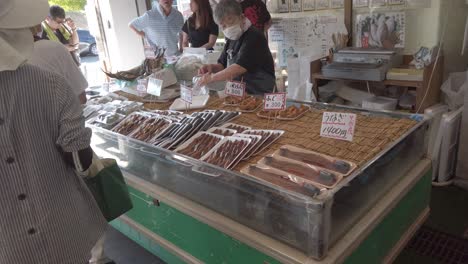 Ältere-Japaner-Kaufen-Rohen-Fisch-Im-örtlichen-Marktladen-Und-Tragen-Eine-Atemmaske