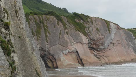 Meereswellen-Krachen-Gegen-Tiefe-Moosige-Schichten-Freiliegender-Gesteinsschichten-Am-Strand-Von-Itzurun,-Zumaia,-Spanien