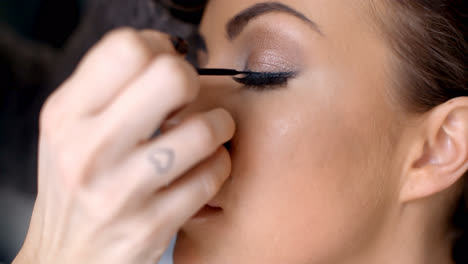 Pretty-woman-applying-eye-liner-on-her-eyelid