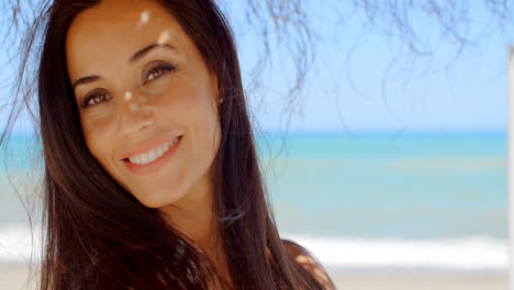 Mujer-Bajo-Una-Sombrilla-De-Playa-Sonriendo-A-La-Cámara