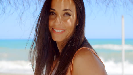 Mujer-Bajo-Una-Sombrilla-De-Playa-Sonriendo-A-La-Cámara