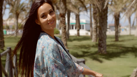 Mujer-Sonriente-Apoyada-Contra-La-Barandilla-En-La-Playa.