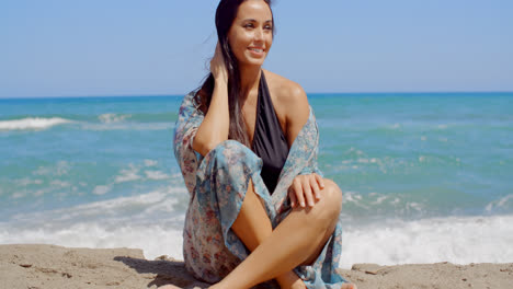 Mujer-Atractiva-Sonriente-Sentada-En-La-Arena-De-La-Playa