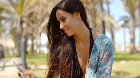 Happy-Lady-at-Grassy-Beach-Ground-Using-Her-Phone