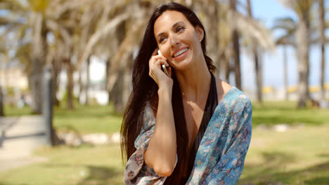 Happy-Lady-at-Grassy-Beach-Ground-Talking-on-Phone