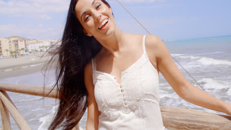 Mujer-En-La-Barandilla-De-La-Playa-Riéndose-De-La-Cámara.