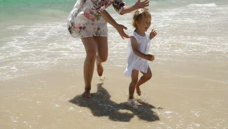 Kleines-Mädchen-Läuft-Mit-Ihrer-Mutter-Am-Strand-Entlang