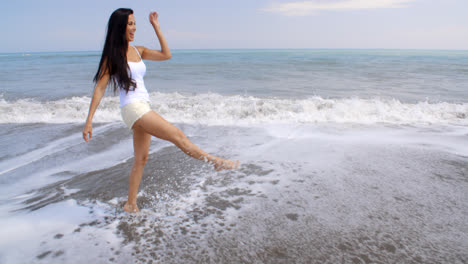 Unbeschwerte-Frau,-Die-Am-Tropischen-Strand-Wasser-Aufwirbelt