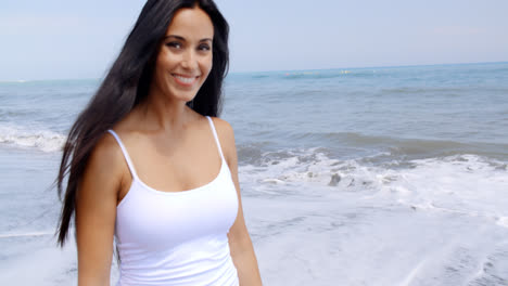 Mujer-Caminando-Por-La-Playa-Y-Sonriendo-A-La-Cámara