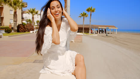 Brunette-Woman-Sitting-on-Beach-Promenade-Wall