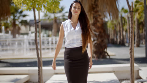 Elegant-young-woman-walking-through-a-park