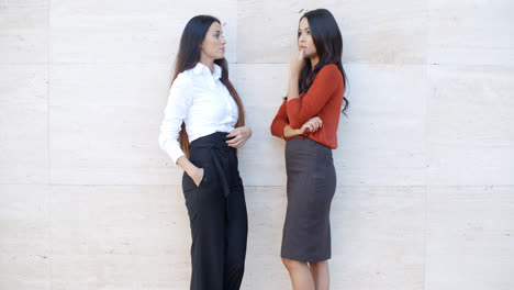 Two-businesswomen-standing-chatting-outdoors