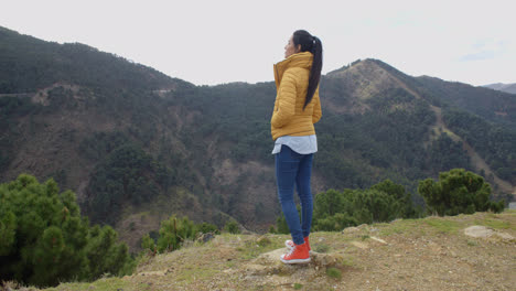 Woman-in-yellow-coat-near-mountain-valley