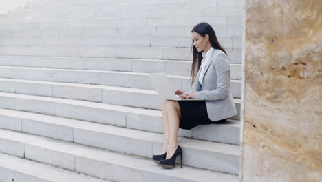 Mujer-Sonriente-Usando-Laptop-En-Las-Escaleras