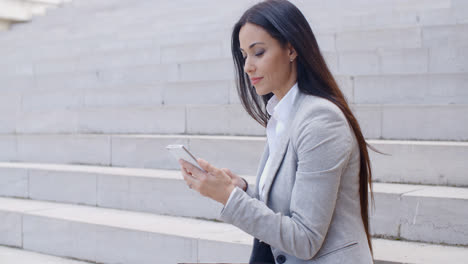 Pretty-young-worker-sitting-on-steps-with-phone